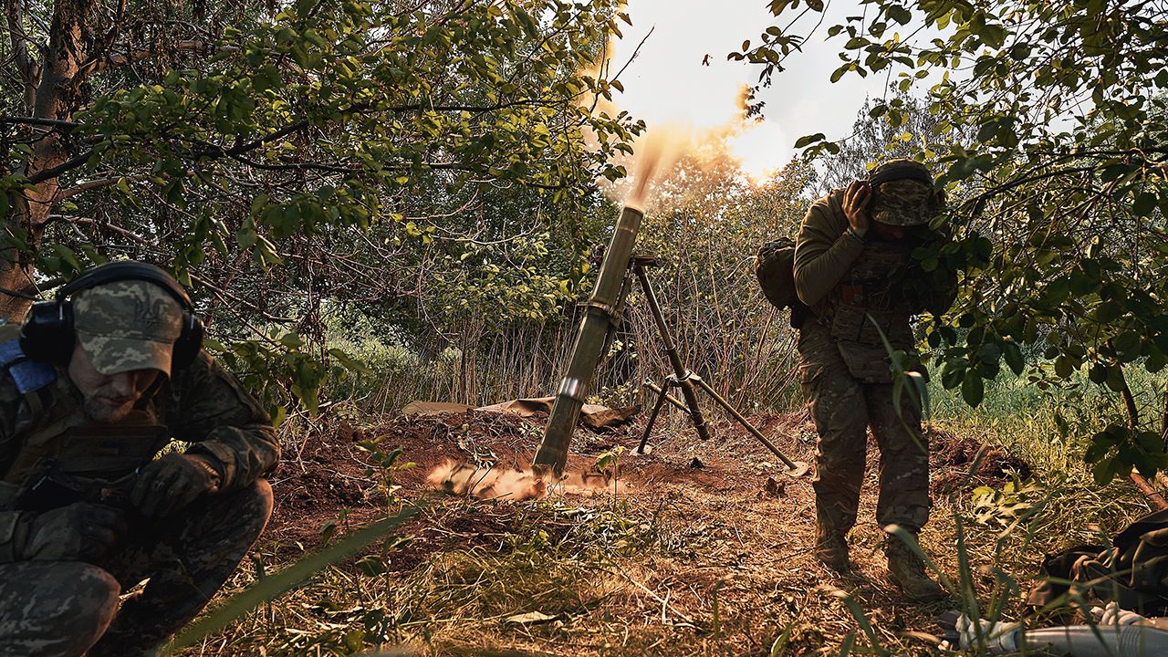 A soldier turns his back and covers his ears after setting off a mortar in Chuhuiv Raion, Kharkiv Oblast, Ukraine.