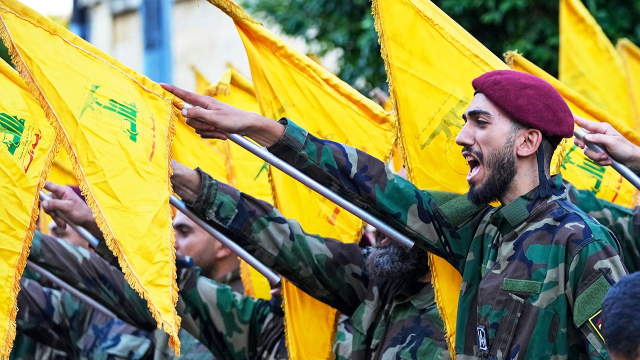 Hezbollah members raise their group flags and chant slogans as they attend the funeral procession of Hezbollah commanders in Beirut