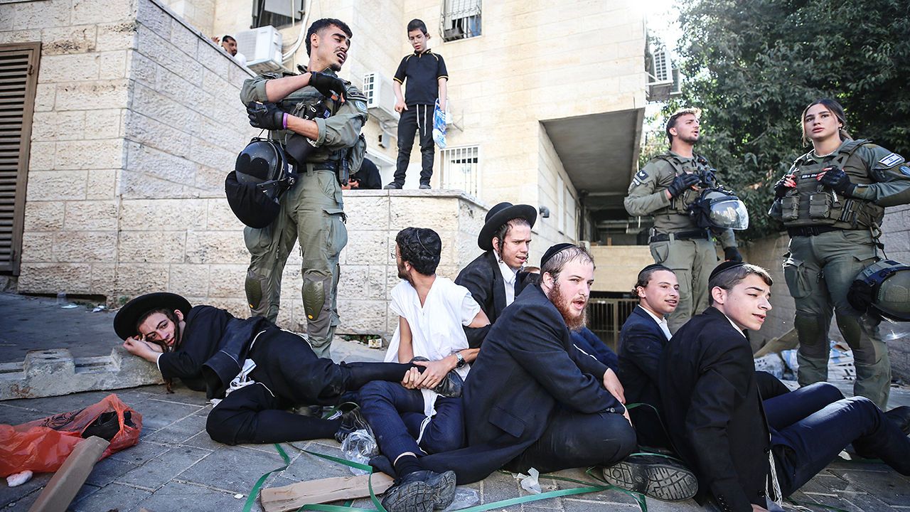 Israeli soldiers stand next to a group of Orthodox men