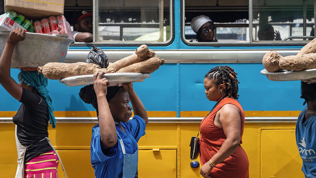 Street vendors pass a stationary bus in the Makola district of Accra, Ghana.